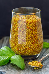 Wall Mural - Mustard sauce with grains in a glass jar.