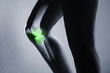 Human knee joint and leg in x-ray, on gray background. The knee joint is highlighted by green colour.