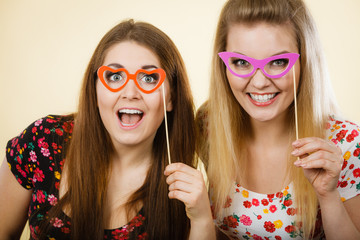 Poster - Two happy women holding fake eyeglasses on stick