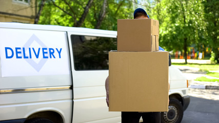 Delivery workman holding many cardboard boxes, express parcel shipment service