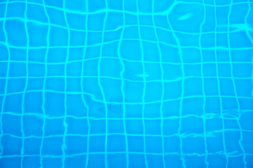 Tiles under water of swimming pool with water ripples.