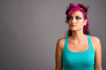 Beautiful woman with pink hair and make-up against gray backgrou