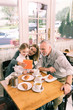 © zinkevych - Beaming grandparents. Happy beaming grandparents eating morning croissants with cute little granddaughter