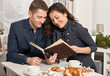 romantic couple drinking tea with cookies, talking and looking photo album