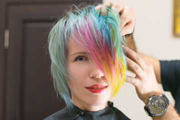 Woman 30-40 smiles and made coloring of hair in different colors in a hairdressing salon. Change the image of a woman.