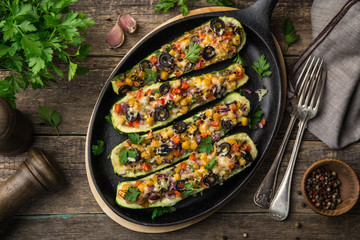 Wall Mural - Stuffed zucchini boats with vegetables ( tomato, pepper, corn, red onion and olives) and cheese in cast iron pan