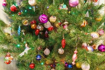 Fragment of big green festive Christmas tree decorated with many colorful toys. Beautiful new year background