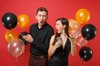 © ViDi Studio - Couple stand back to back messaging in cellphone celebrating birthday holiday party isolated on red background air balloons. St. Valentine International Women Day Happy New Year 2019 concept. Mock up.
