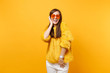 Laughing young woman with closed eyes in fur sweater and heart orange glasses keeping hand near head isolated on bright yellow background. People sincere emotions, lifestyle concept. Advertising area.