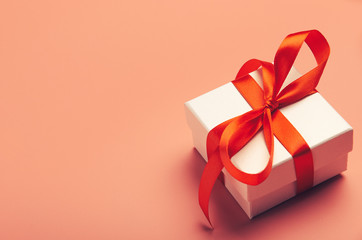 White gift box with red bright ribbon on red background. Beautiful gift for the new year, Christmas, birthday. Copy space