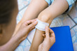 © M-Production - Woman puts adhesive bandage on child knee.