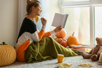 Woman reading book at home on autumn day