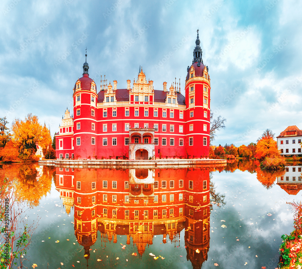 Bad Muskau Park and Palace - Famous UNESCO World Heritage site in Germany and Poland. Amazing Seasonal Autumn landscape with reflections of Great Classic architecture in Pond waters. Yellow leaves. - obrazy, fototapety, plakaty 