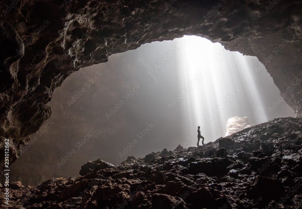 A silhouette inside the beautiful cave Goa Jomblang in East Java, Indonesia - obrazy, fototapety, plakaty 