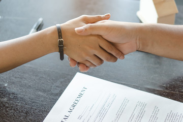 Business deal done. Above view of client handshakes with property agent after signed contract agreement rent apartment.