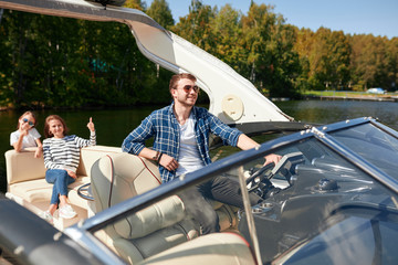 Young father with adorable daughter and wife resting on big boat