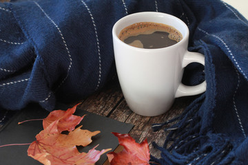 Coffee, book, scarf and red maple leaves on vintage wooden background. Autumn drink concept. October, November, fall foliage