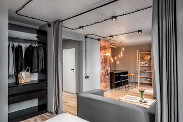 Modern living room in loft style made in grey colors with sofa and kitchen on the background