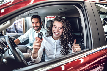 Smiling woman holding up the key of his new car