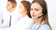 © rogerphoto - Call center operators. Focus on young cheerful smiling woman in headset. Business and customer service concepts