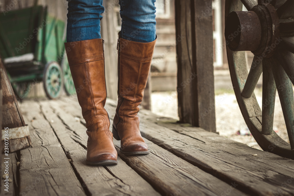 Walking on wooden floor with leather boots on old retro ranch.  - obrazy, fototapety, plakaty 