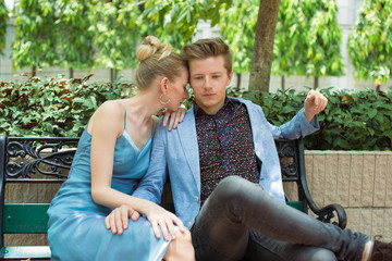 Confident young man sitting on the bench in the park with  woman