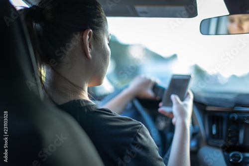 Fotografia, Obraz Texting and driving. Woman using phone behind the wheel in car.