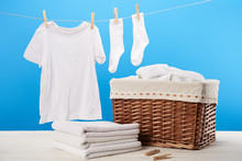 Laundry Basket, Pile Of Clean Soft Towels And White Clothes Hanging On Clothesline On Blue