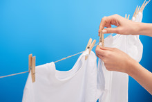 Cropped Shot Of Person Hanging Clean Clothes With Clothespins On Clothesline Isolated On Blue