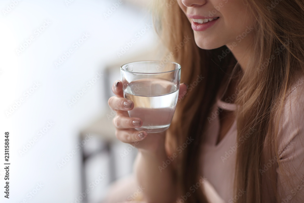 Beautiful young woman drinking water at home, closeup