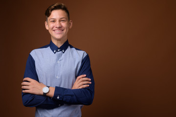 Studio shot of young handsome teenage boy against brown backgrou