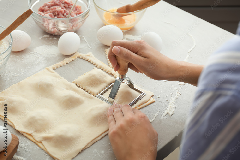 Woman making tasty ravioli on table