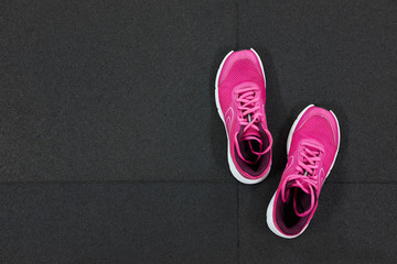 Wall Mural - Pair of pink running sneakers for woman on a black background. Top view