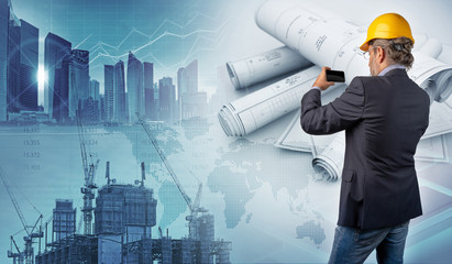 architect holding a smartphone and blueprints in urban background