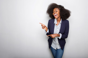 Canvas Print - happy young african american woman pointing fingers against gray background