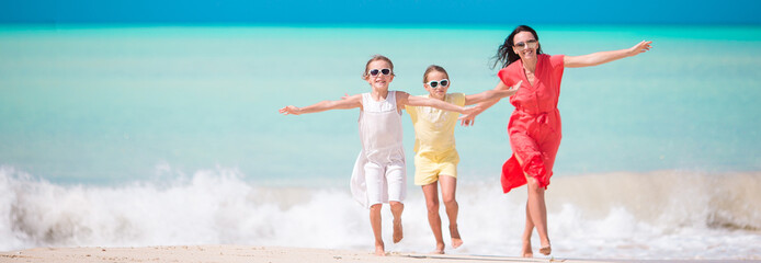 Beautiful mother and her adorable little daughters on the beach