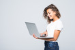 © F8  \ Suport Ukraine - Young mixed race cool woman with curly hair using laptop and smiling isolated over white background