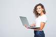 © F8  \ Suport Ukraine - Young mixed race cool woman with curly hair using laptop and smiling isolated over white background