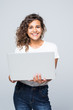 © F8  \ Suport Ukraine - Young mixed race cool woman with curly hair using laptop and smiling isolated over white background