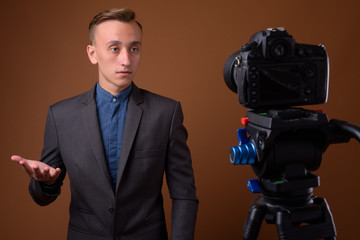 Studio shot of young handsome businessman against brown backgrou