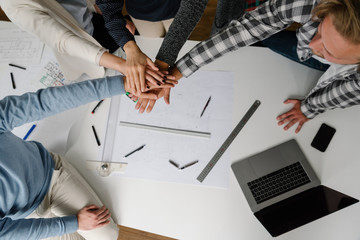 Wall Mural - Group of people stacking hands above office desk with success on their mind