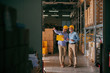 © Dusan Petkovic - Colleagues walking in storage and checking documentation, on heads helmets. Younger worker pointing on boxes.