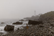 Woman Walking Along A Foggy Coast With Lighthouse