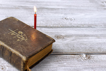 Catholic bible and red church burning candle on wooden background with copy space