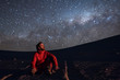 A young adult man seating and looking at the view of our Milky Way galactic core located in the constellation of Sagittarius, an amazing view at Atacama Desert. Chile
