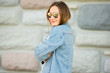 © Anastasia - Portrait of a beautiful girl in casual white t-shirt, jeans jacket and sunglasses on the brick wall background .folded her arms