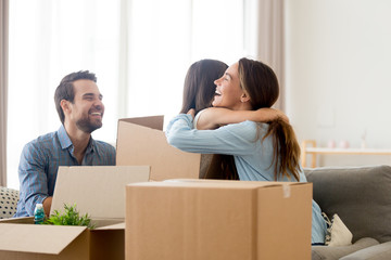 Canvas Print - Happy mother embrace small daughter family sitting on sofa in living room with heap of cardboard boxes at new home. Relocation and moving or remodeling, buy or rent new house mortgage and loan concept