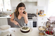 © Stocksy - Woman making and tasting home made chocolate cake with blueberri