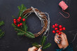 Rustic Christmas grapevine wreath. Female hands make Christmas wreath with natural spruce branches. top view, blank space 