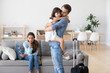 © fizkes - Unhappy diverse family in living room at home. Sad father hugs hold on hand small daughter, mother sitting on sofa. Parents divorcing, child stay with mommy dad leave with suitcase. Break up concept